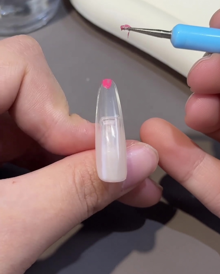 Un ongle en cours de catalysation sous une lampe UV/LED, montrant la surface du gel durcie.