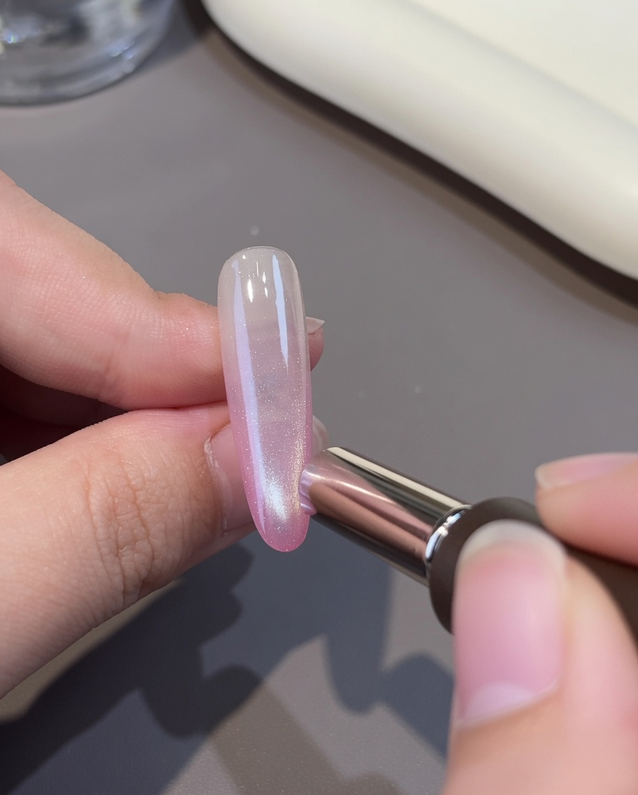 Une couche de gel œil-de-chat blanc appliquée sur la base rose de longle.