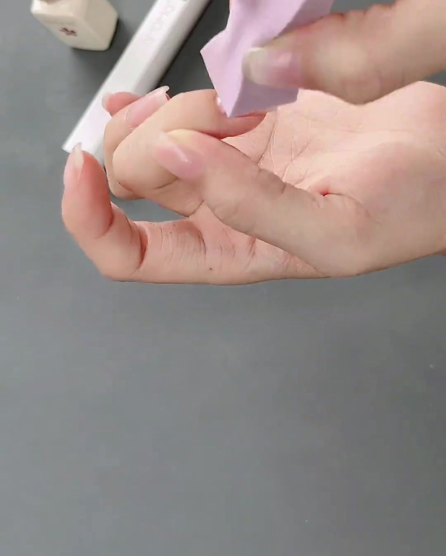 Une éponge à maquillage applique du gel blanc sur un ongle naturel pour créer un effet dégradé léger.