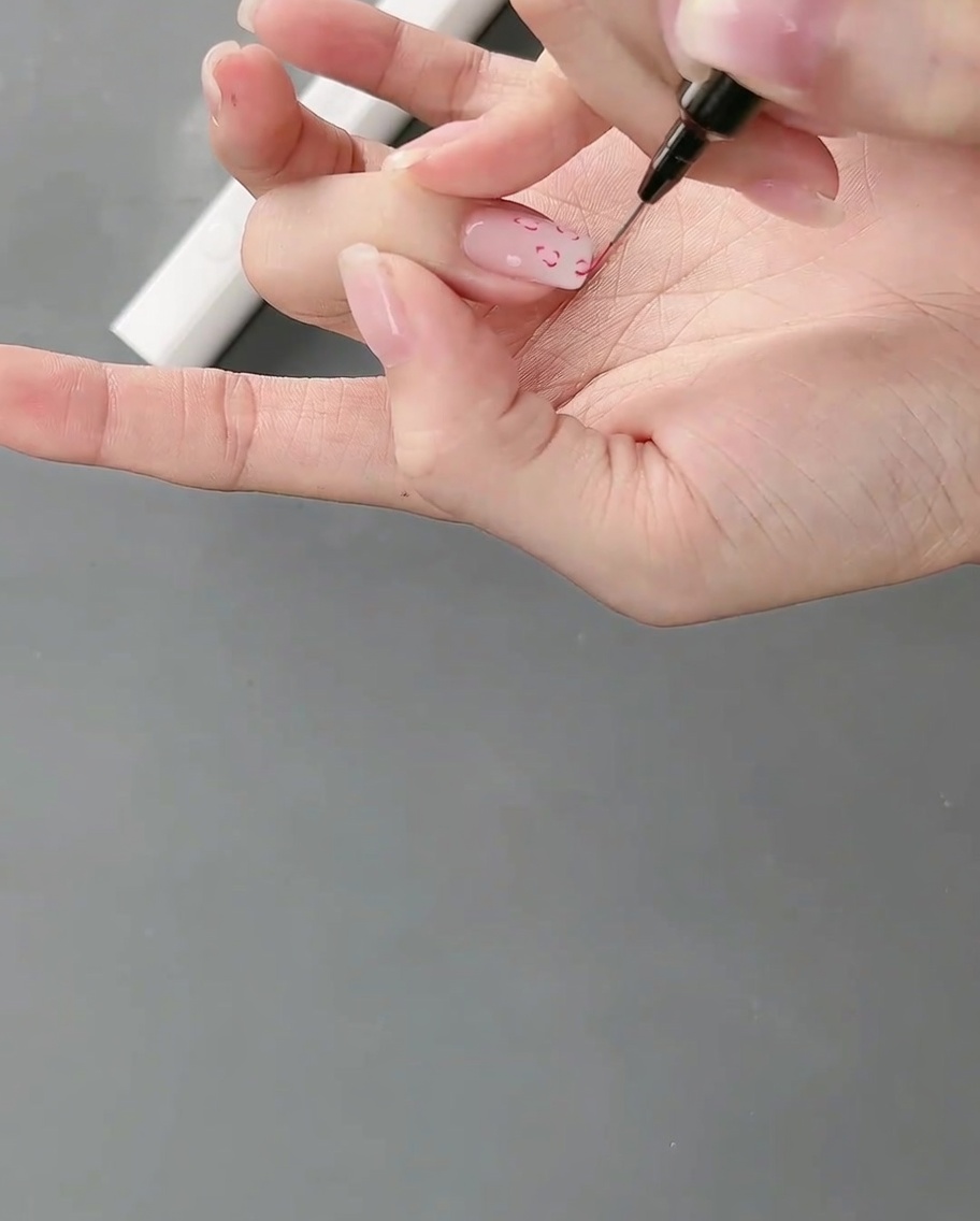 Une main placée sous une lampe à ongles, catalysant le nail art aux lignes fines fraîchement peint.