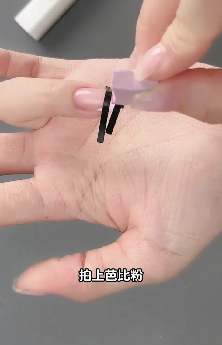 Un petit outil éponge tapotant du vernis gel rose clair sur la grille créée par lautocollant sur un ongle.