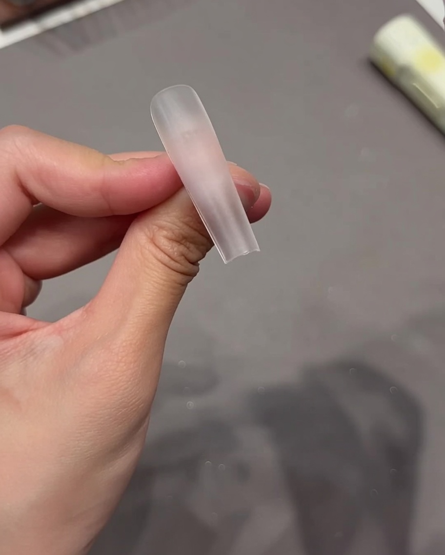 Gros plan dune main appliquant une languette adhésive transparente sur la surface dune capsule dongle.