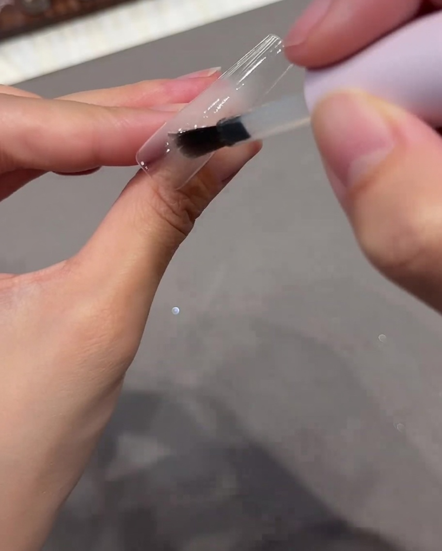 Un pinceau appliquant une couche de base transparente sur une capsule dongle.