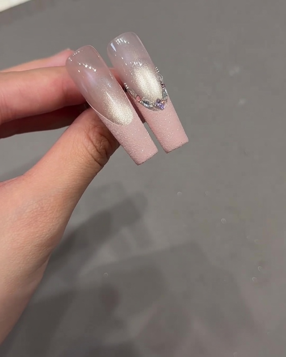 Gros plan dun ongle avec un motif French détaillé comportant une variété de strass alignés le long de la pointe.