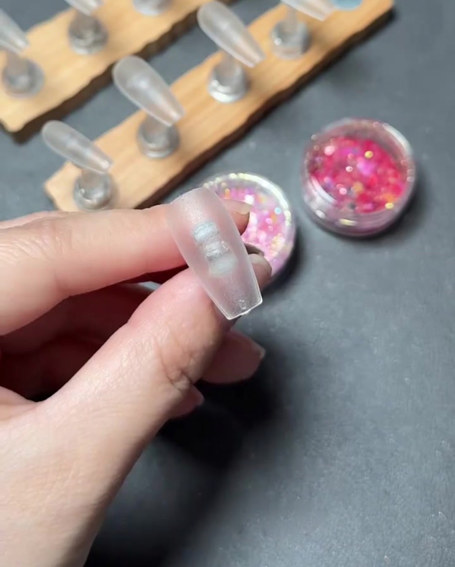 Un gros plan dun pinceau appliquant un gel de base transparent sur la surface dune capsule dongle en plastique transparent.