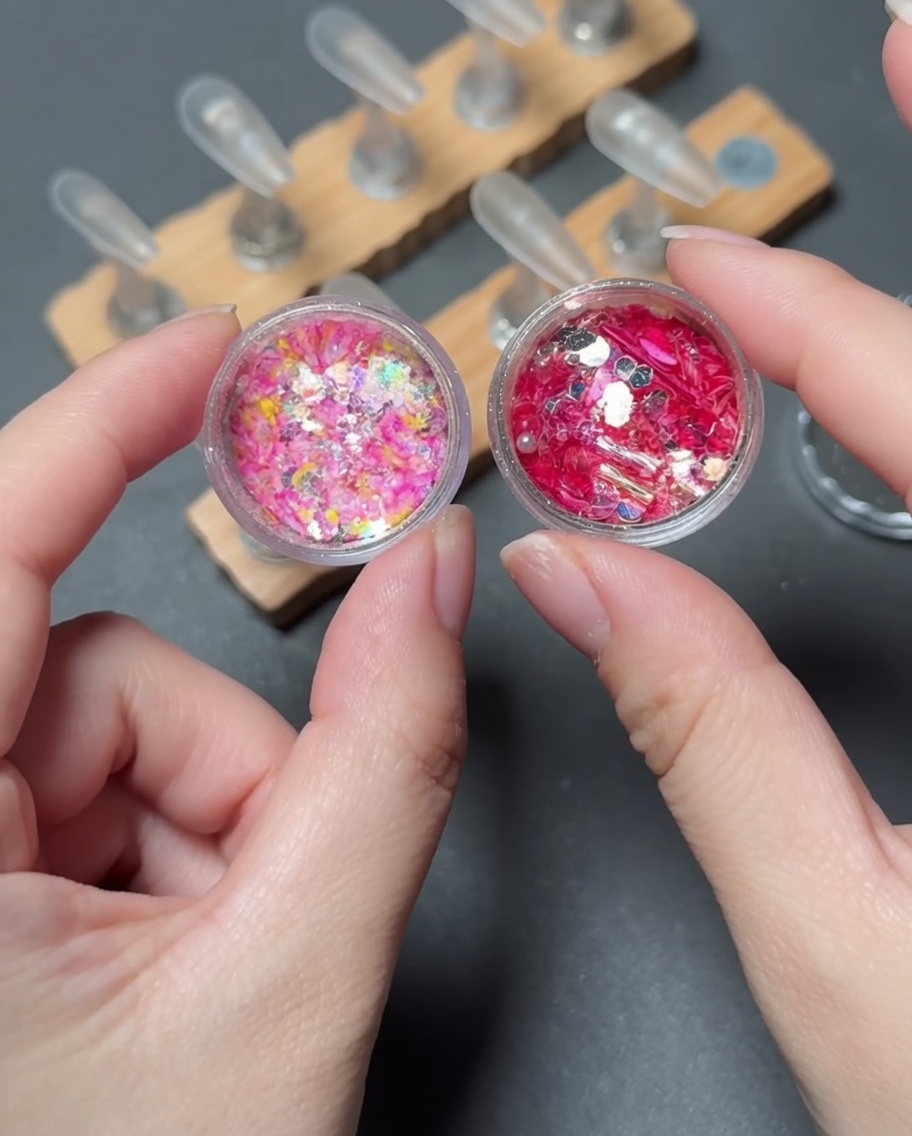 Un pinceau déposant des paillettes vibrantes et multicolores sur la pointe dun faux ongle.