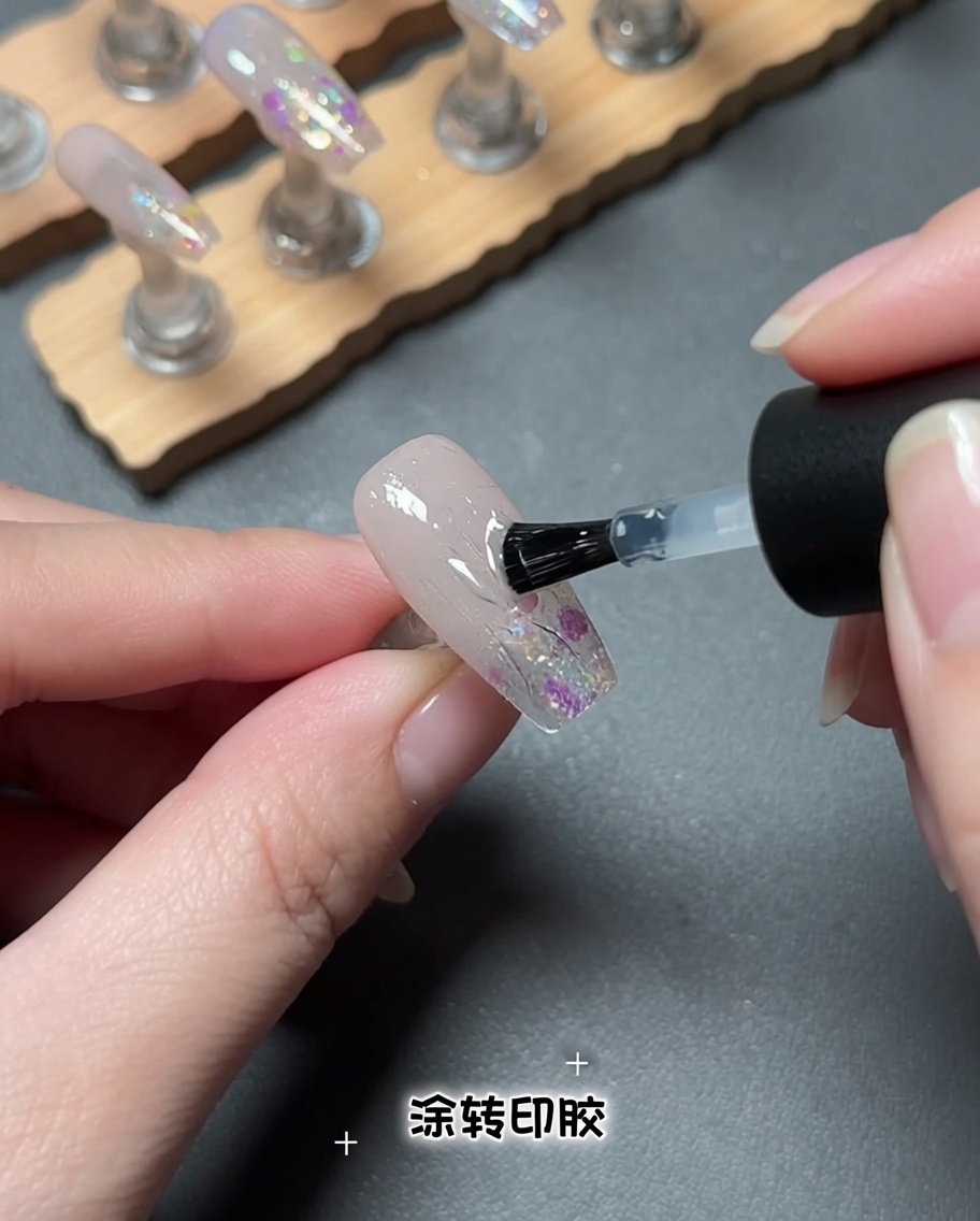Un pinceau appliquant un produit en gel transparent sur la surface dun ongle.