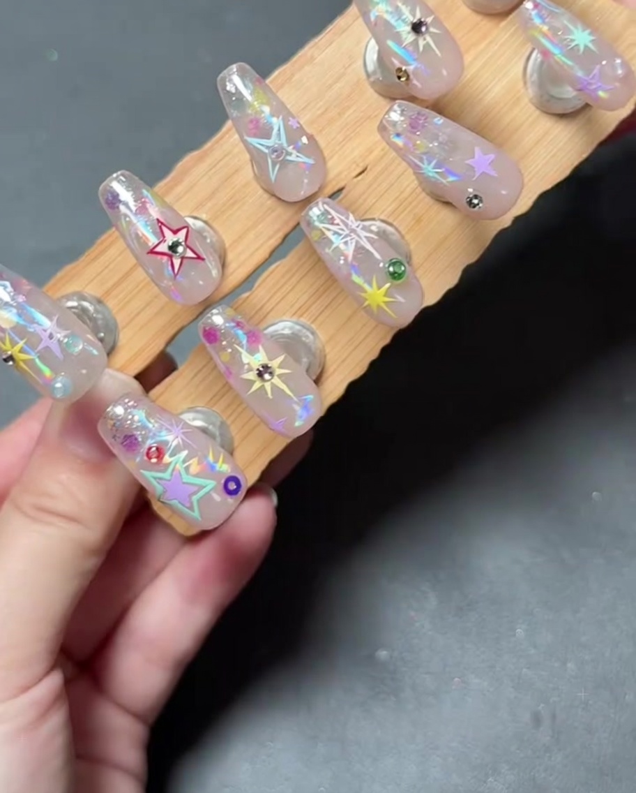 Un gros plan dune main plaçant un petit strass sur un ongle décoré à laide dun outil.