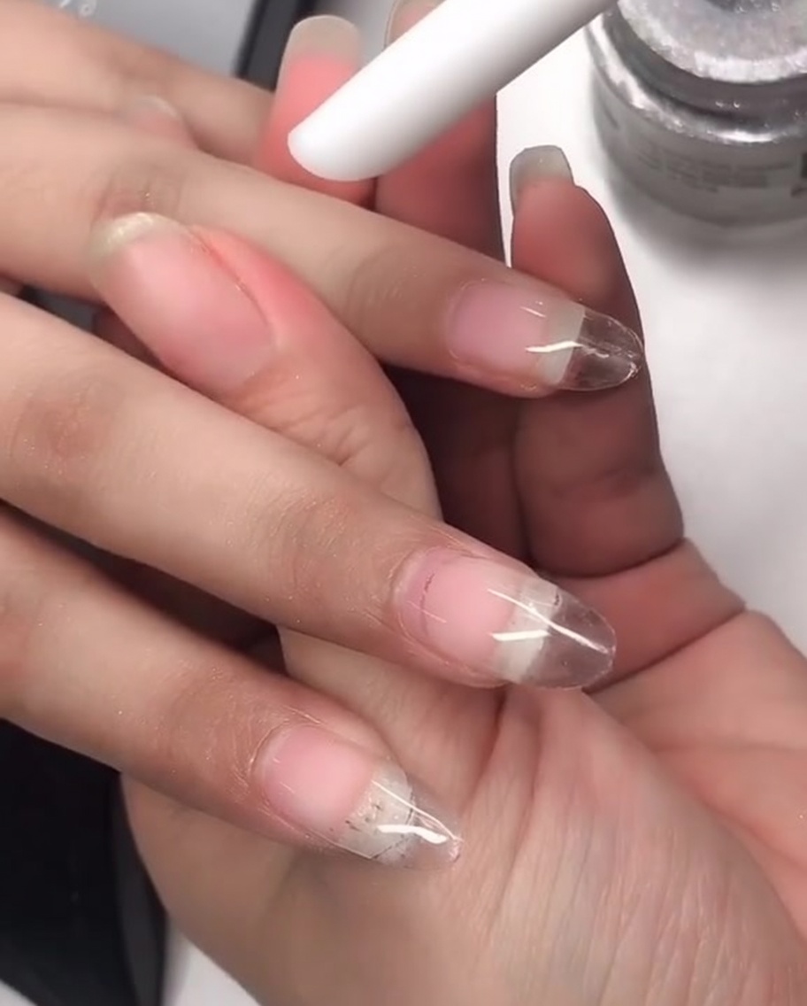 Un outil en silicone utilisé pour frotter la poudre chrome laser sur la surface dun ongle manucuré.