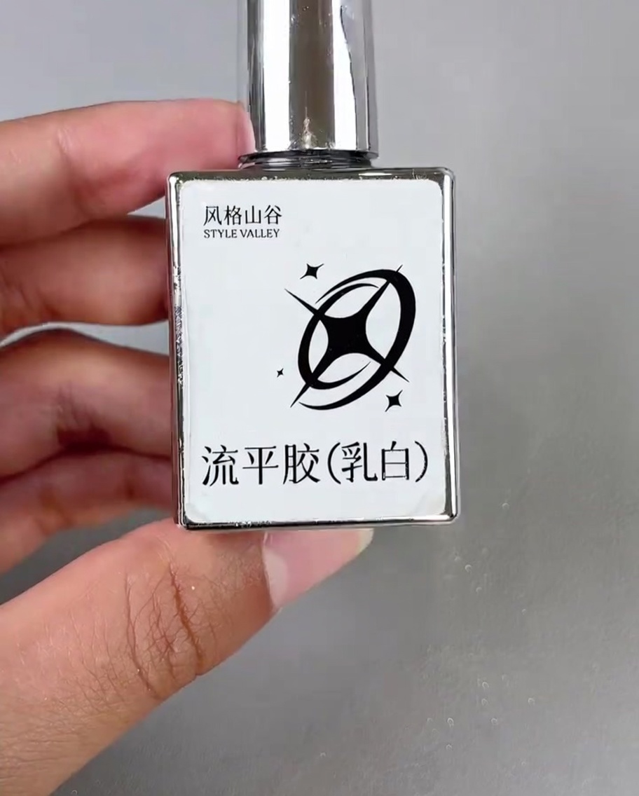 Un petit pinceau appliquant une goutte de gel blanc lacté dans le coin dun ongle décoré.