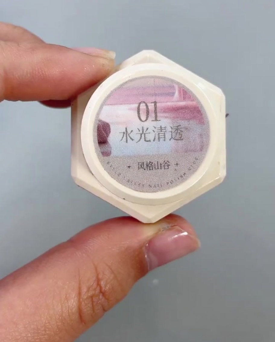 Un pinceau appliquant un gel cat-eye transparent et scintillant sur la moitié inférieure dun ongle.