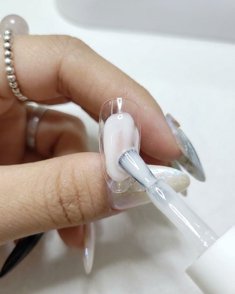 Un pinceau appliquant un top coat transparent brillant sur une capsule dongle.
