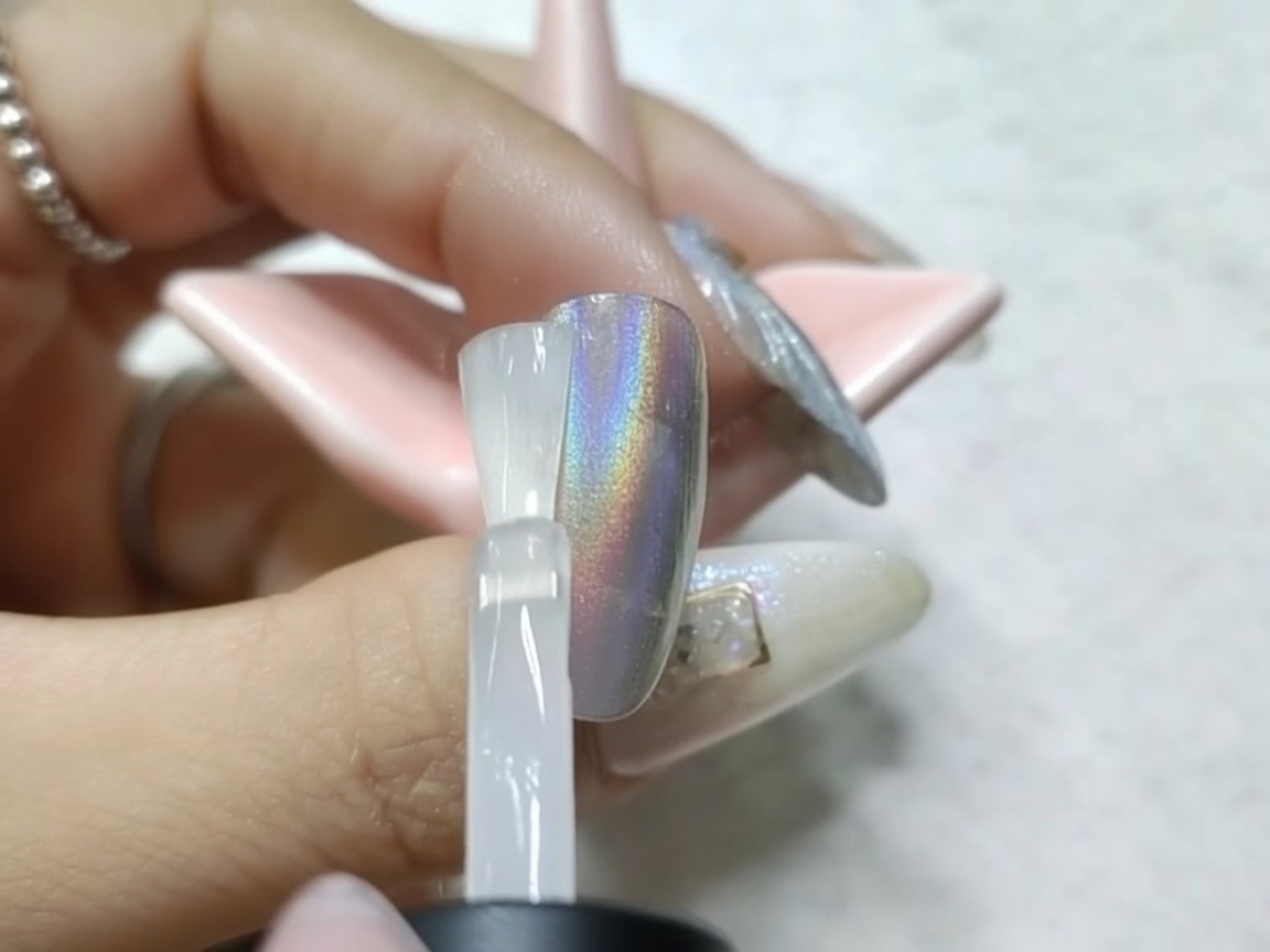 Un ongle avec finition chrome en cours de catalyse sous une lampe UV/LED après application du top coat mat.