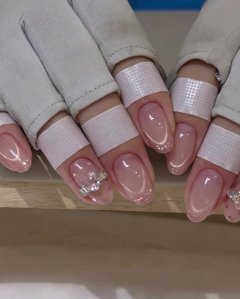 Un pinceau fin trace une ligne de French rose sur un ongle.