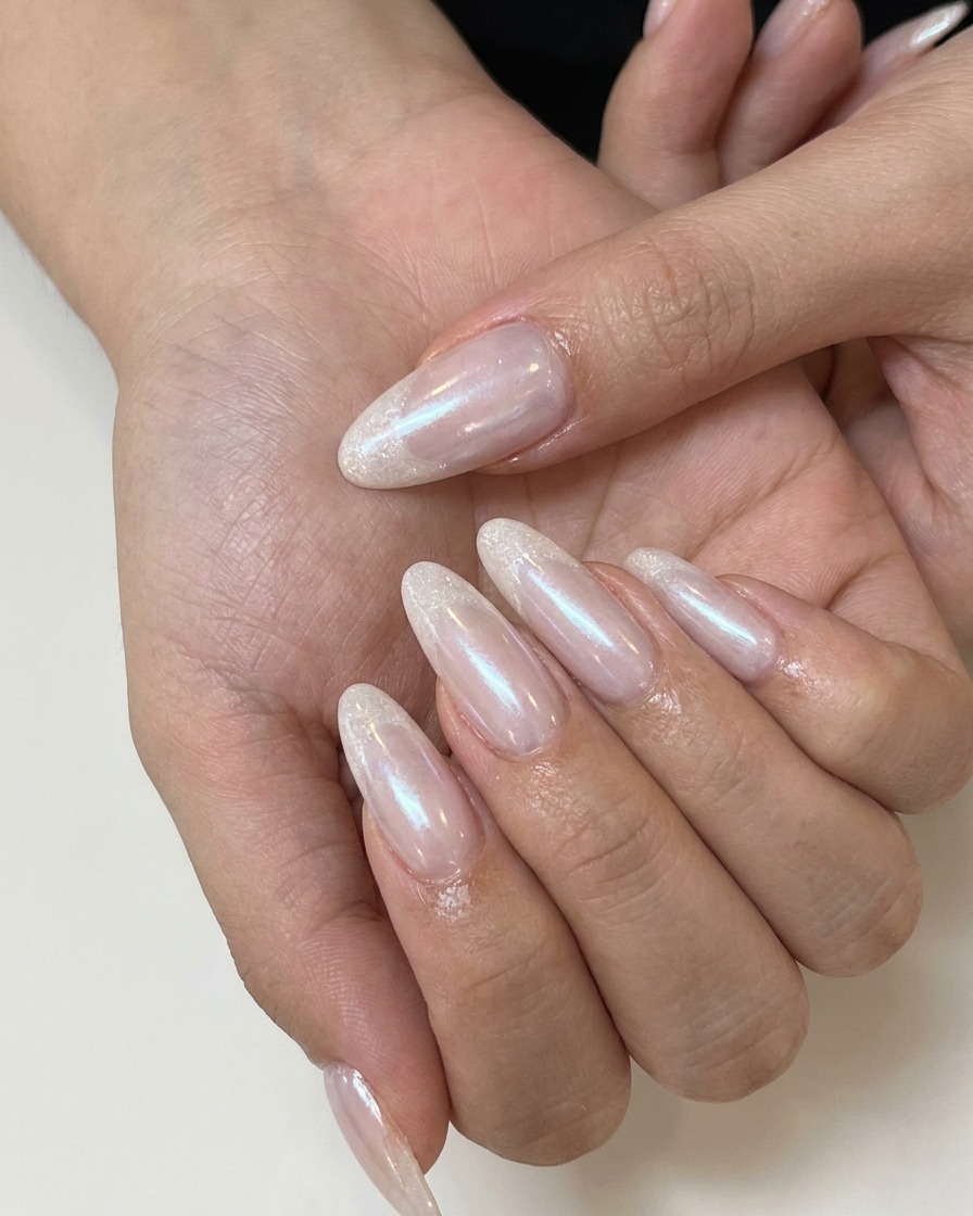 Une prothésiste ongulaire appliquant un top coat mat sur un ongle en gel nude rosé.