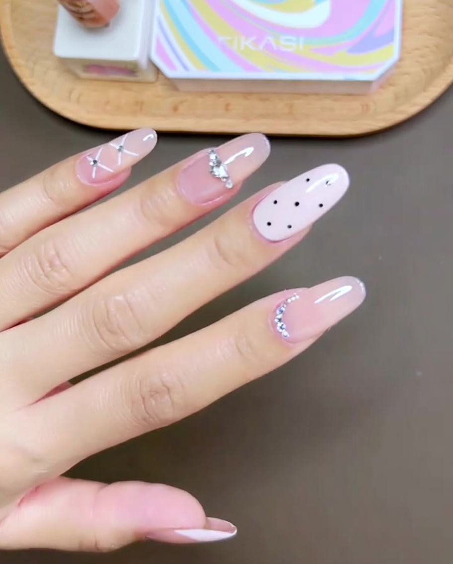 Gros plan dun pinceau de vernis gel rose appliquant la couleur sur longle du majeur.