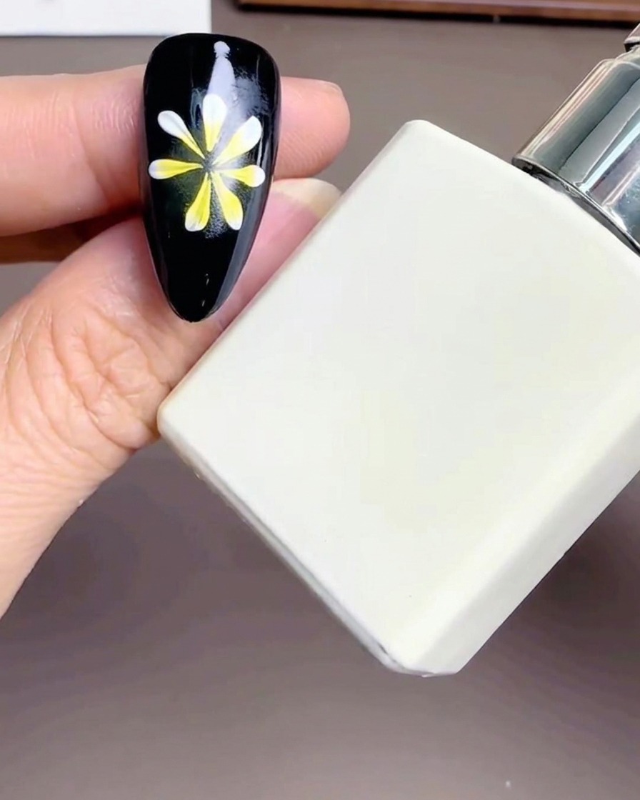 Gros plan dun flacon blanc de Diamond Top Coat près dun ongle décoré.