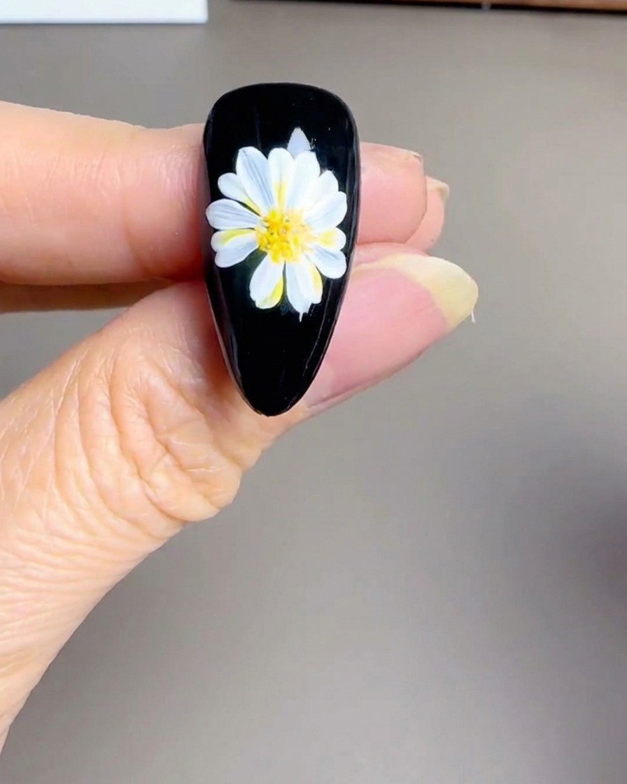 Gros plan dune main utilisant une lampe UV/LED portative sur un ongle noir fini.