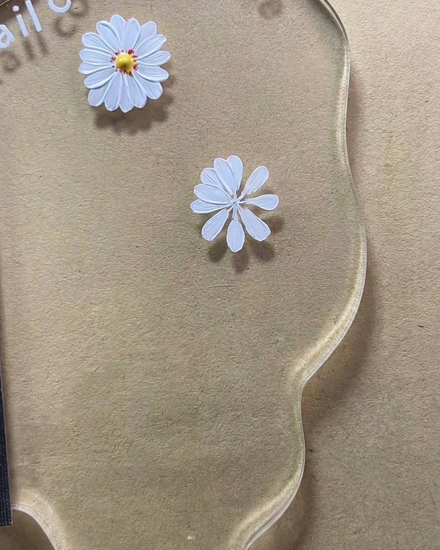 Gros plan dun design de marguerite blanche à huit pétales en cours de finalisation sur une palette de nail art.
