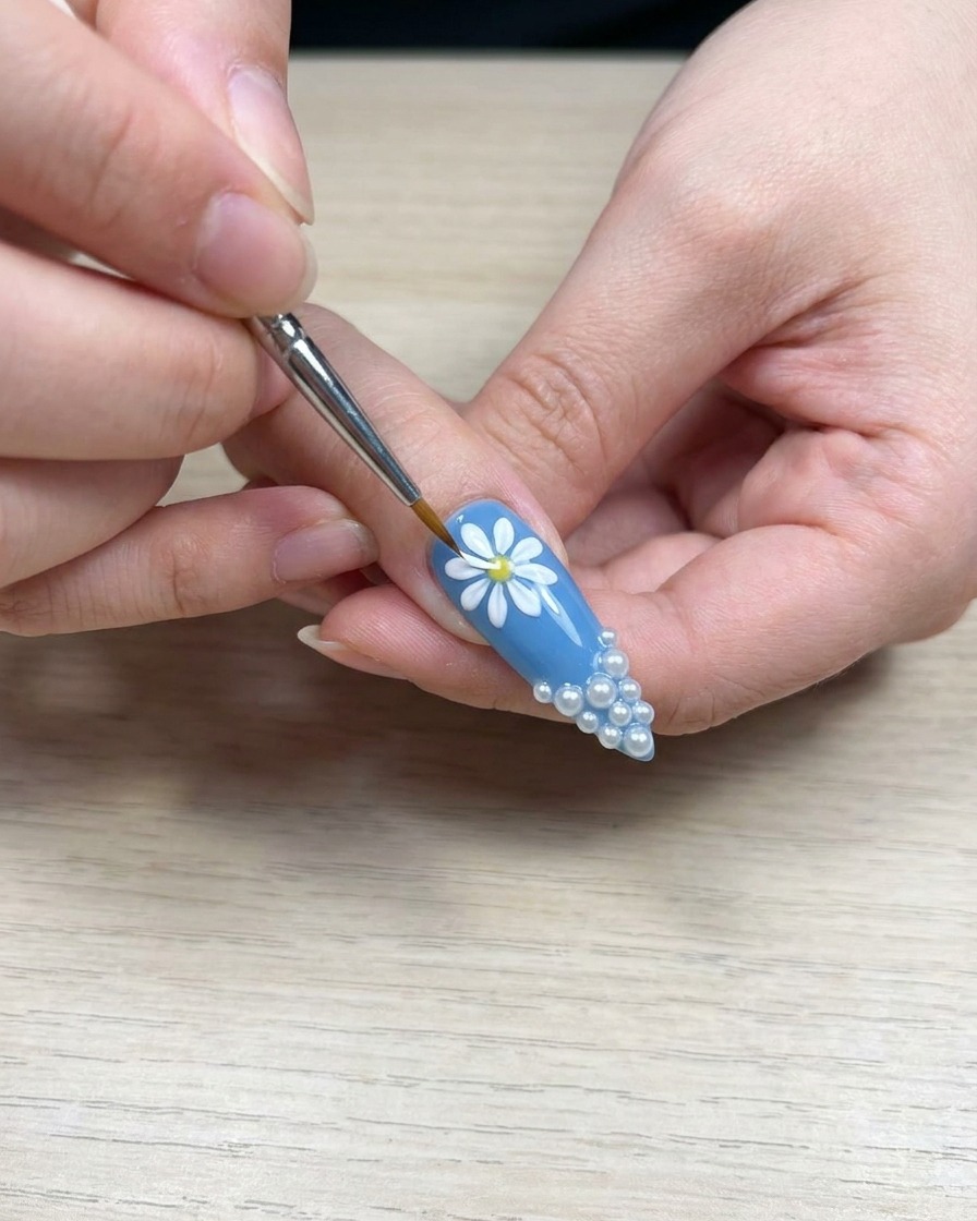Vue de près dun pinceau appliquant du gel blanc sur un pétale de marguerite pour améliorer la densité de la couleur.