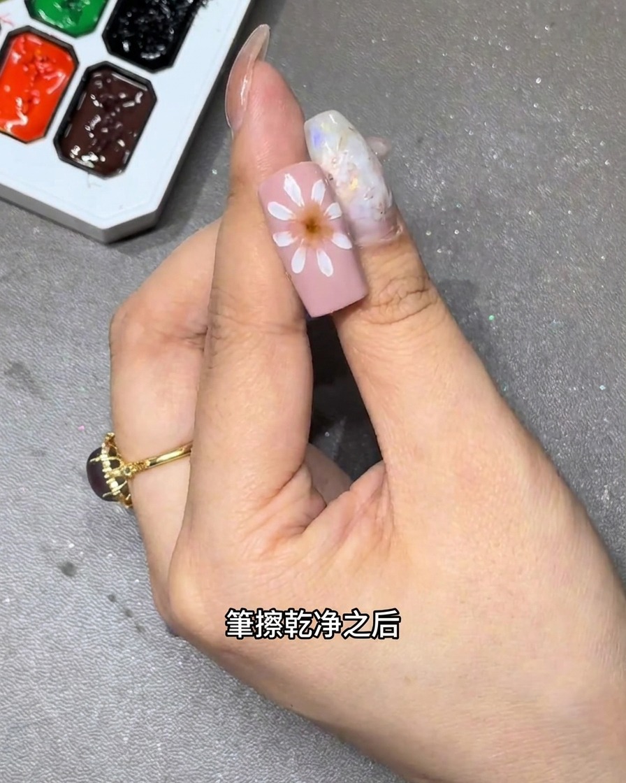 Gros plan dun pinceau estompant des pétales de fleurs blancs sur une base dongle rose pour créer un effet dégradé doux.