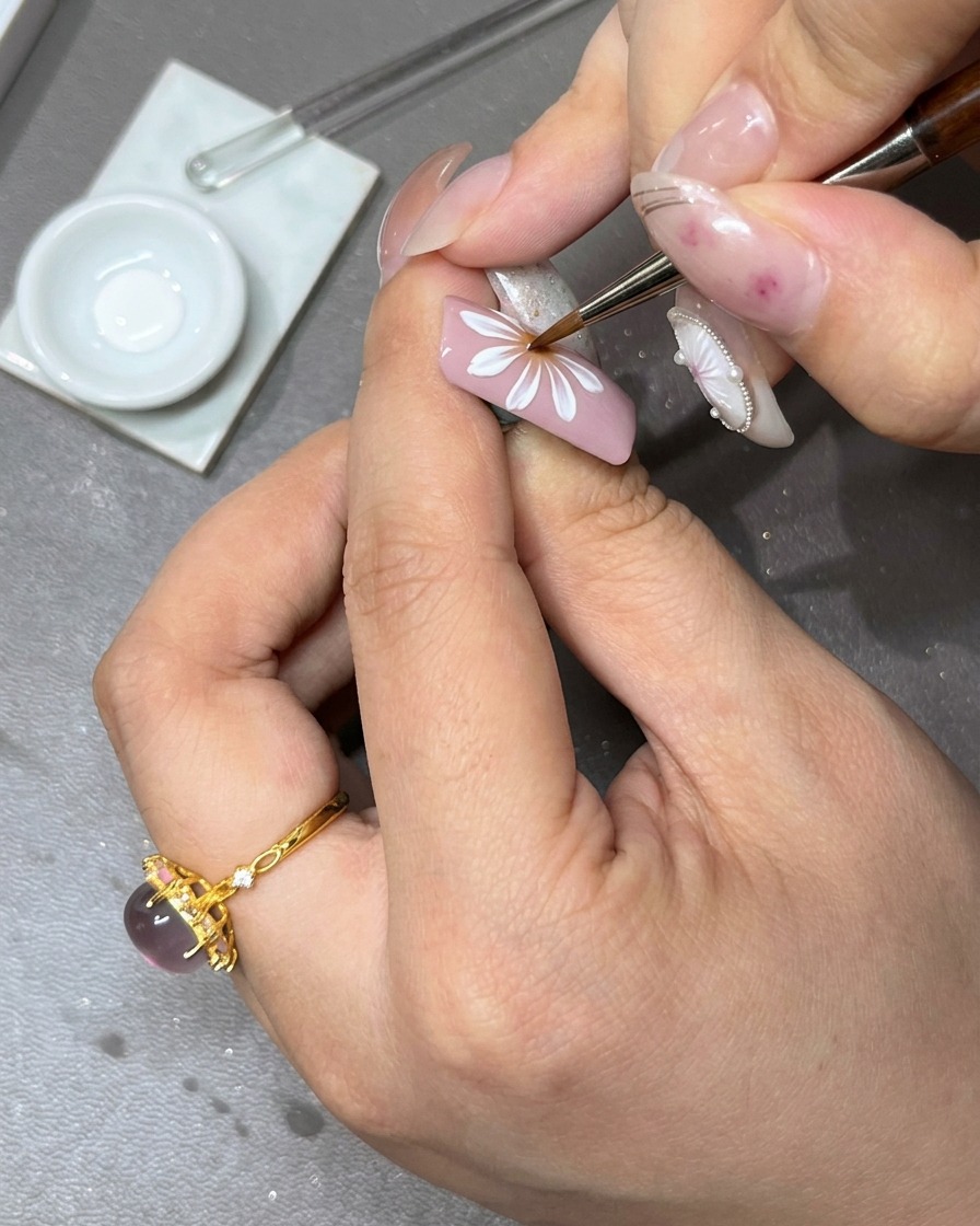 Un pinceau appliquant une deuxième couche de pétales en gel blanc sur la première couche de la fleur pour ajouter de la profondeur.