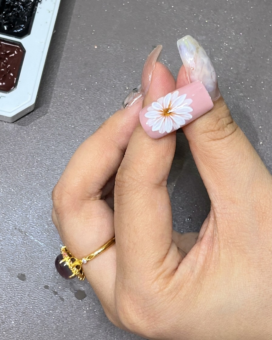 Un point de gel noir placé avec soin au centre de la fleur blanche superposée sur longle.