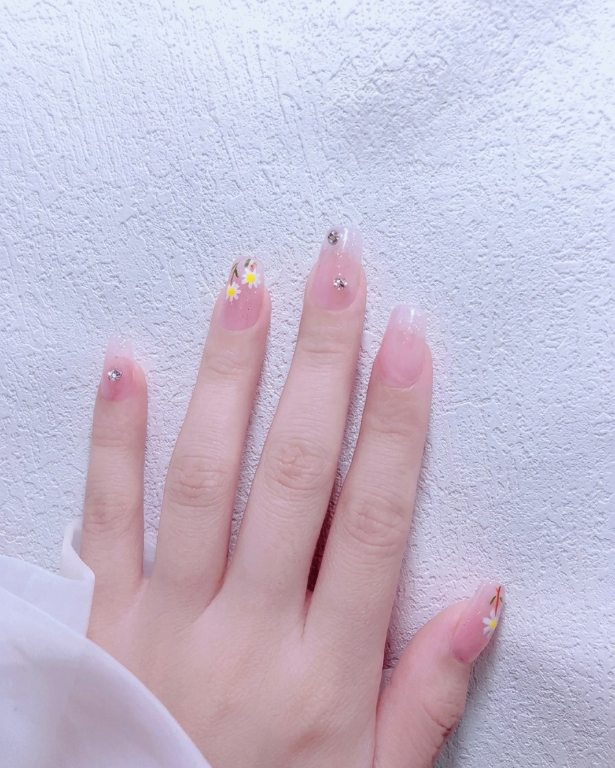 Un pinceau appliquant du vernis gel nude rosé sur un ongle naturel.