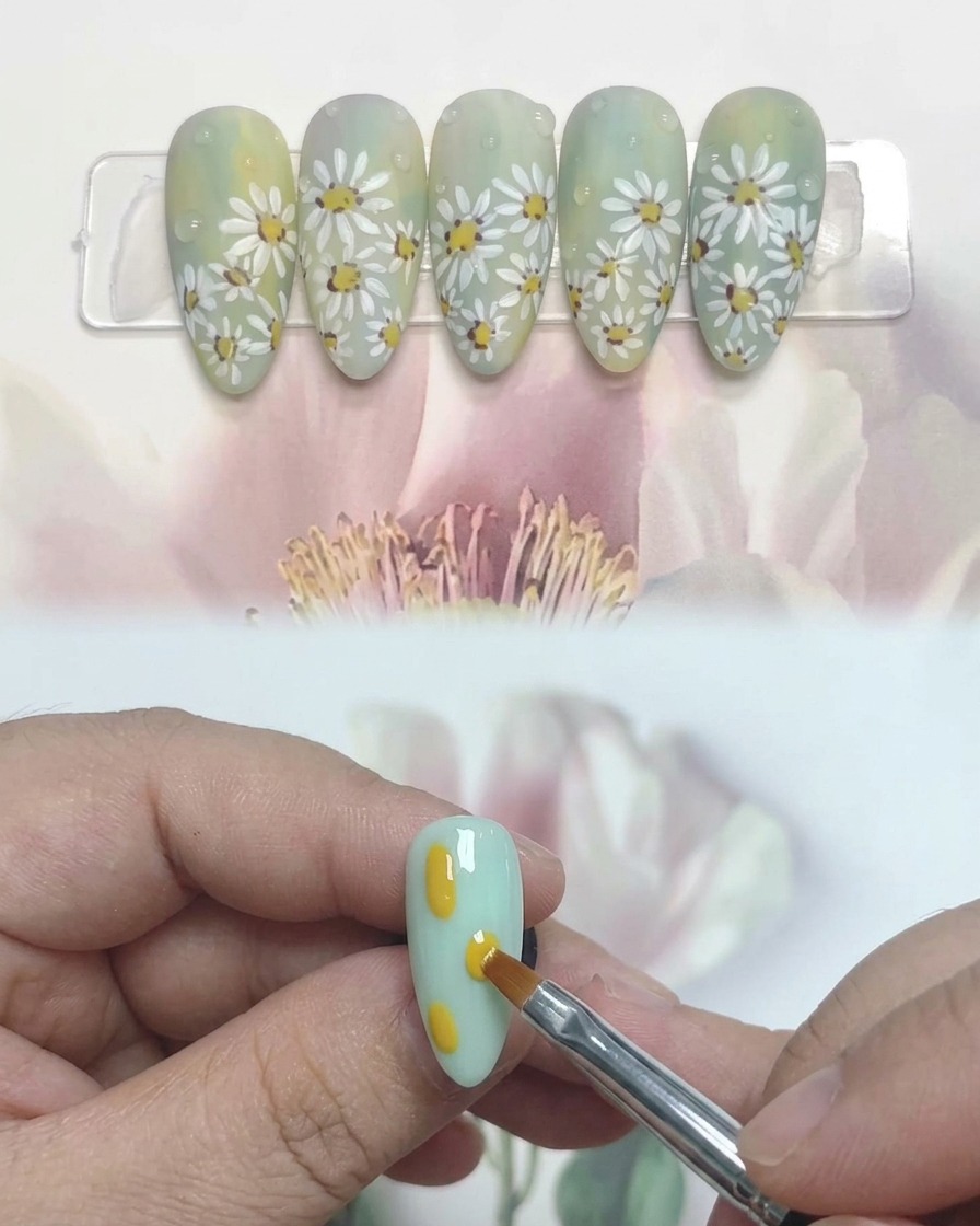 Gros plan dune main avec des ongles décorés de marguerites sous une lampe UV professionnelle.
