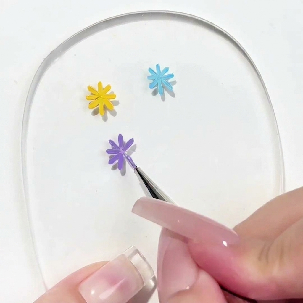 Vue rapprochée dun pinceau de détail appliquant un pétale sur une marguerite violette partiellement terminée.
