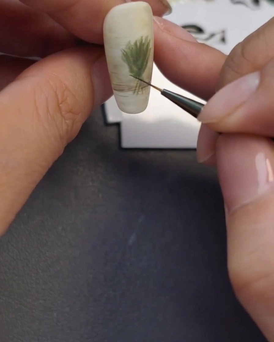 Un pinceau liner créant le contour léger dun vase en verre à la base de longle.