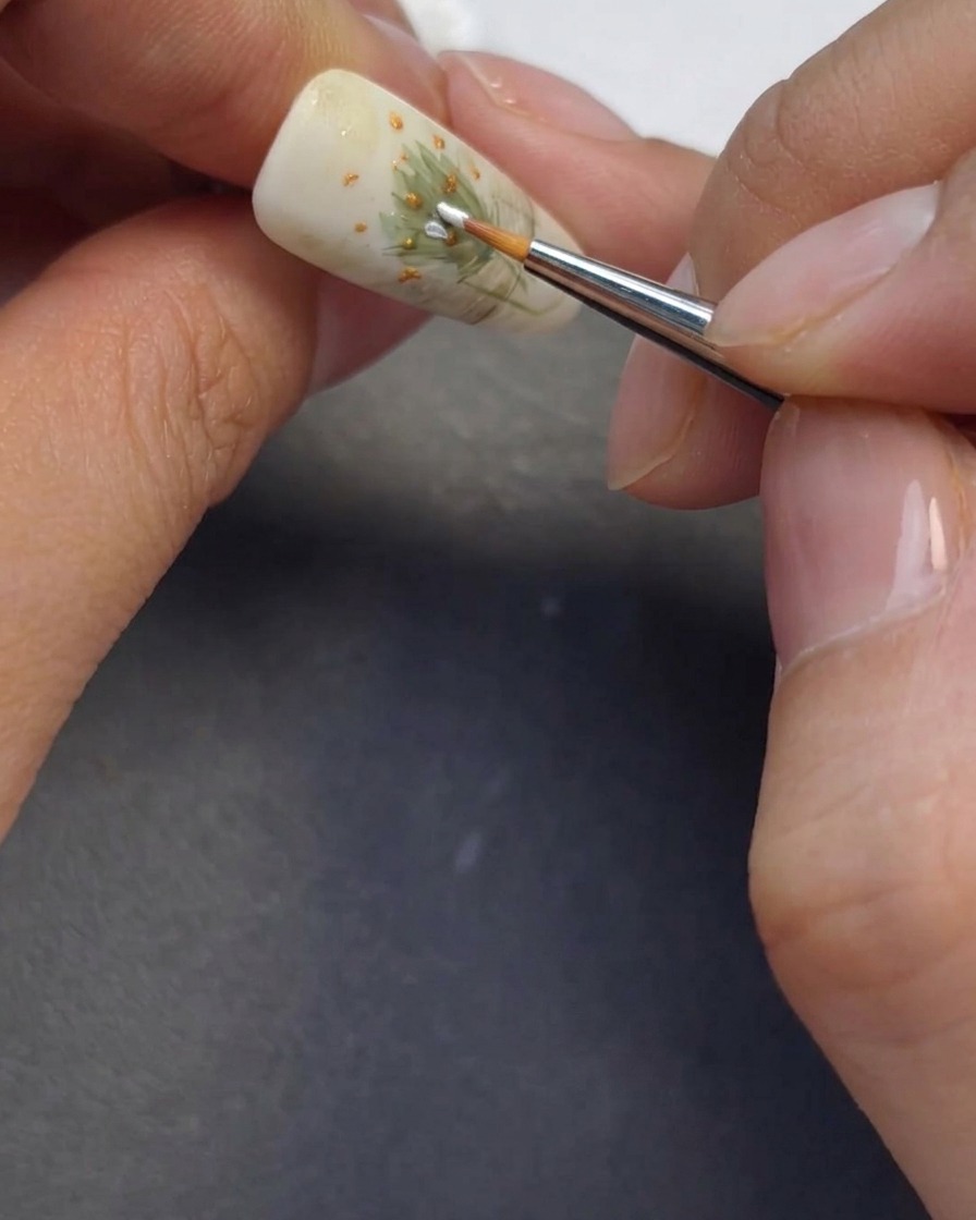 Un pinceau fin peignant des pétales blancs délicats autour des cœurs de fleurs.