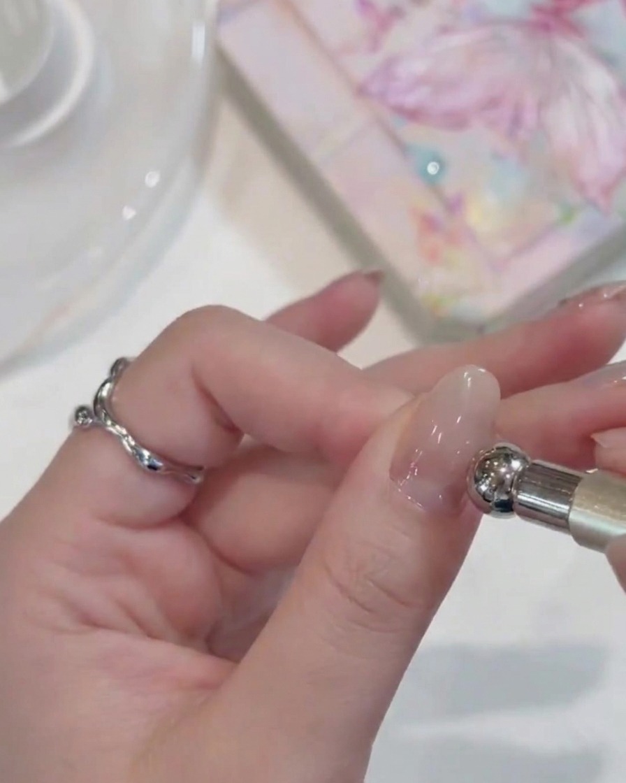 Gros plan dune main avec des ongles vernis placés sous une lampe UV compacte.