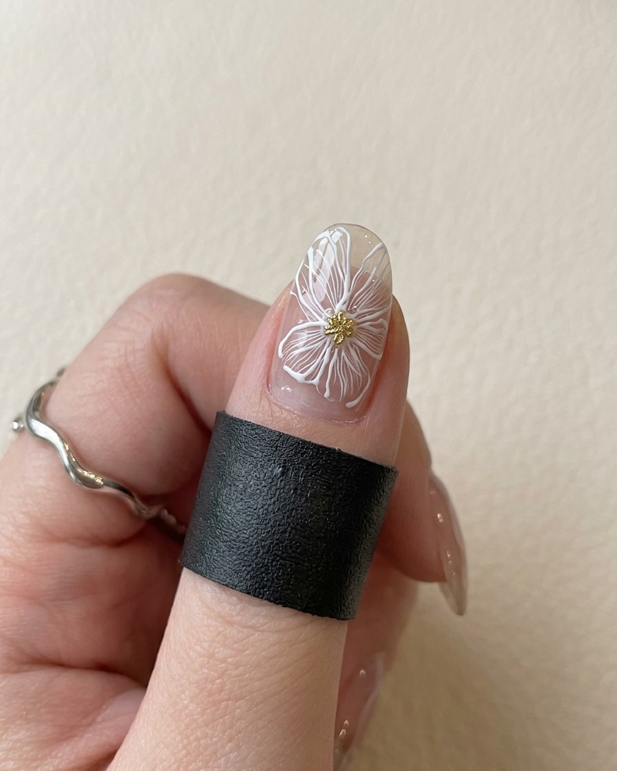 Un ongle avec une fleur blanche et un centre doré placé sous une lampe UV violette pour catalyser.