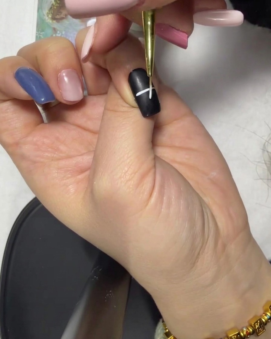 Gros plan montrant une croix blanche formée par lintersection de lignes sur un ongle noir.