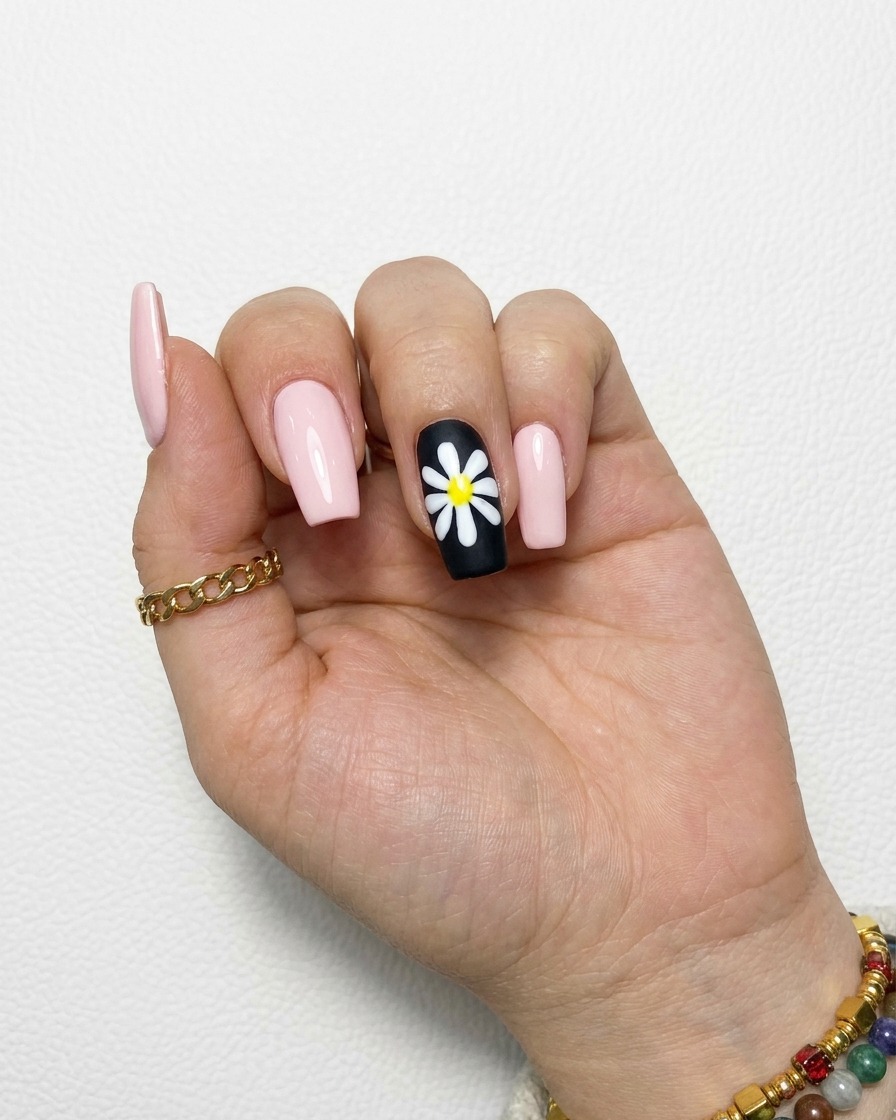 Une marguerite blanche terminée sur un ongle noir avec des pétales opaques.
