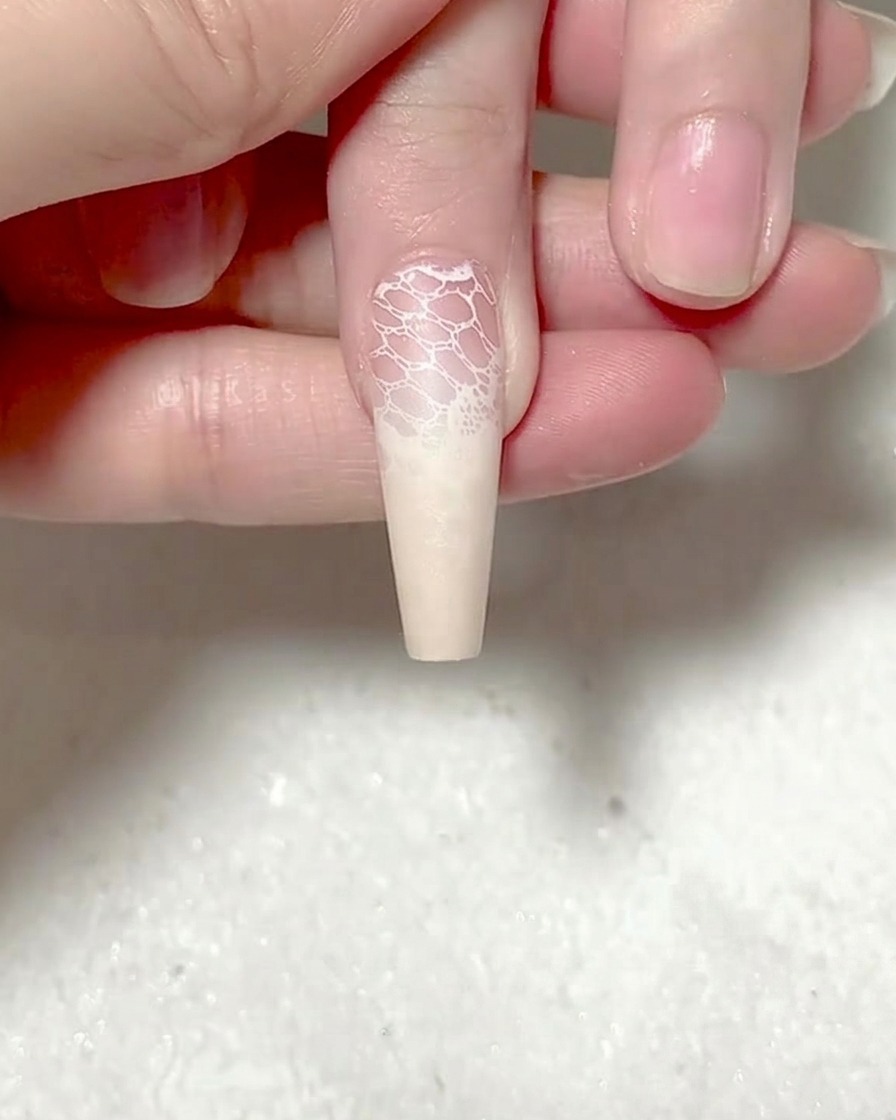 Une pince à épiler plaçant un autocollant de rose rouge sur un ongle.