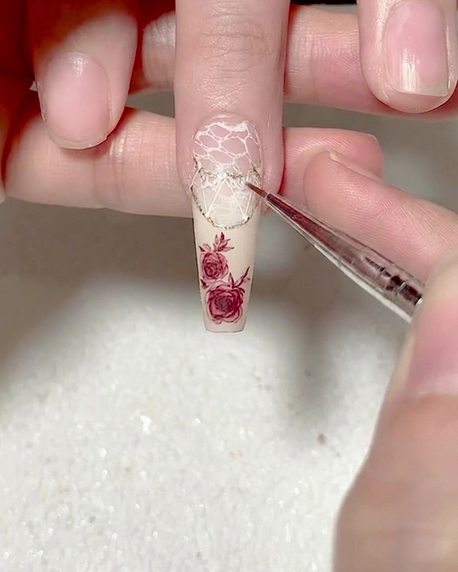 Gros plan dun pinceau liner ajoutant des motifs de dentelle complexes sur le design existant.