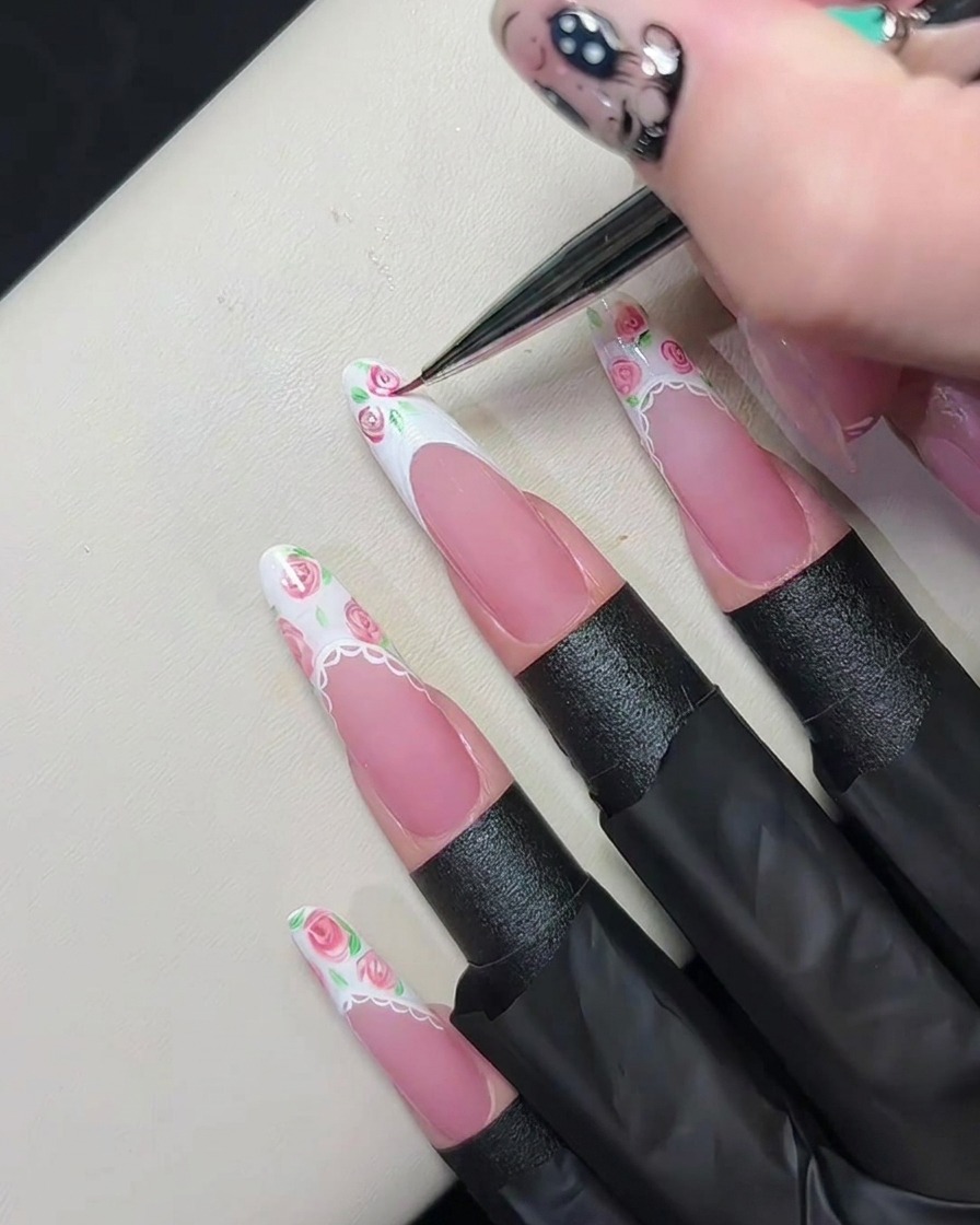 Un pinceau liner fin mélangeant du gel rose dans du gel blanc humide pour créer des motifs de roses.