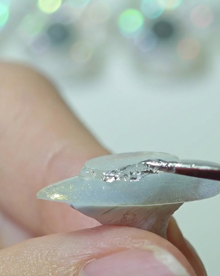 Un outil en silicone pressant un disque en plastique sur le centre dun ongle pour lisser les bords.