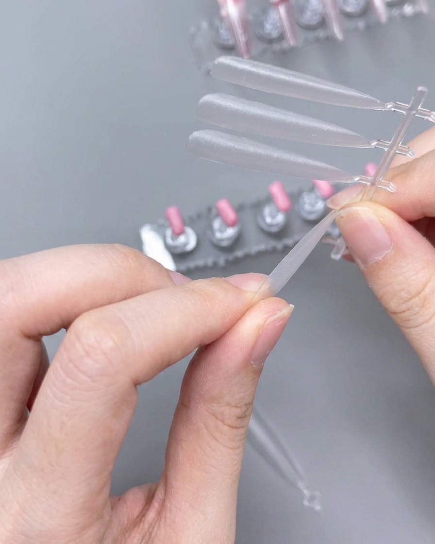 Gros plan sur des mains utilisant une lime pour façonner le bord dune capsule en plastique transparente.