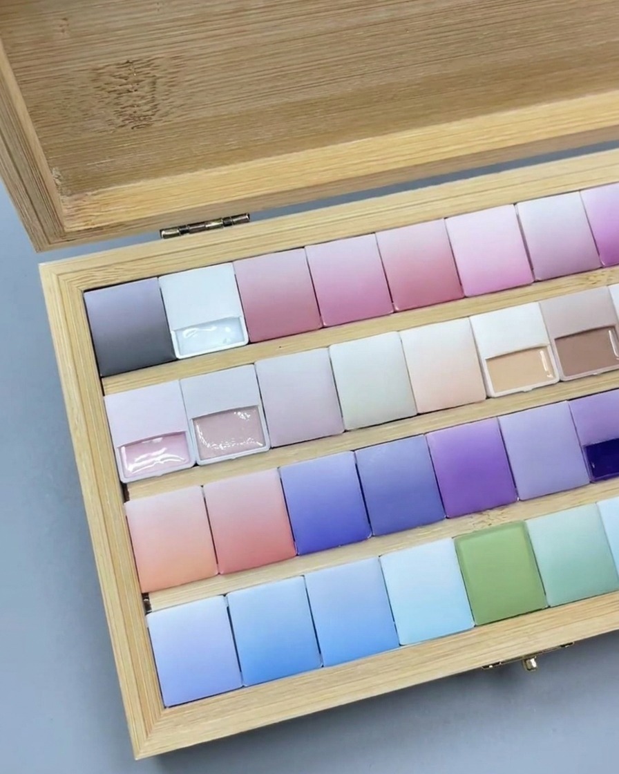 Un pinceau appliquant une fine couche de gel rose translucide sur une capsule transparente.