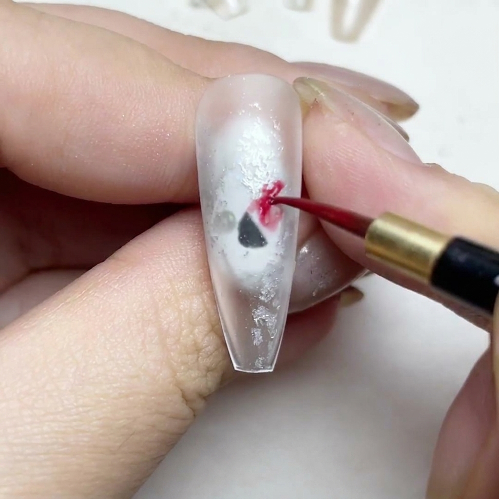 Un pinceau liner fin peignant des pétales de rose aquarelle rouges sur un ongle.