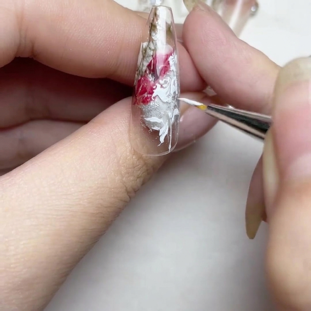 Gros plan dun ongle avec des lignes blanches raffinées et un petit bouton floral détaillé près de lextrémité.