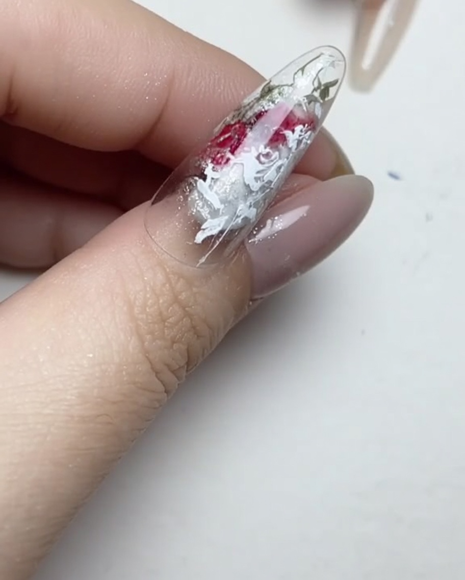 Un pinceau liner appliquant de minuscules points de colle gel transparente sur la surface dun ongle manucuré.