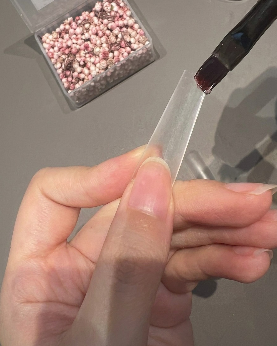 Un pinceau applique une couche de gel adhésif transparent sur la moitié inférieure dune capsule transparente.