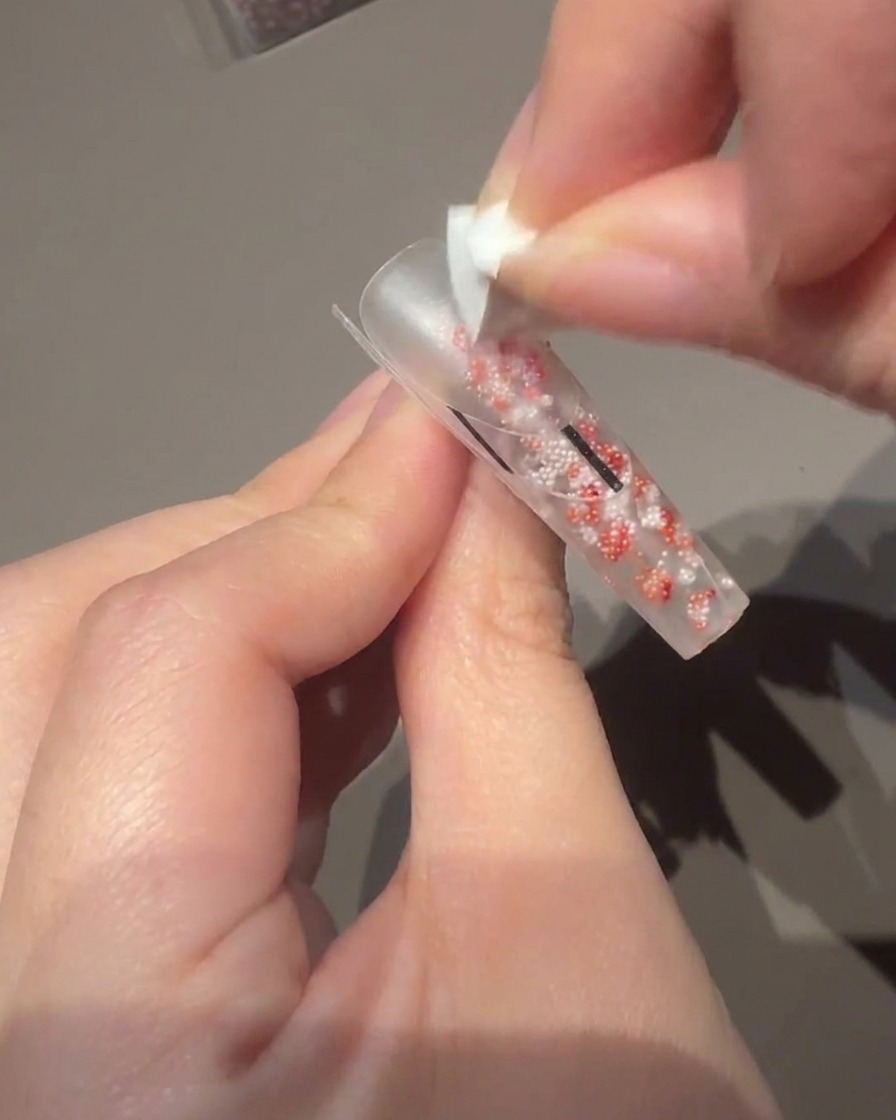 Utilisation dun petit pinceau à gel pour appliquer un vernis rose laiteux sur la plaque de longle.