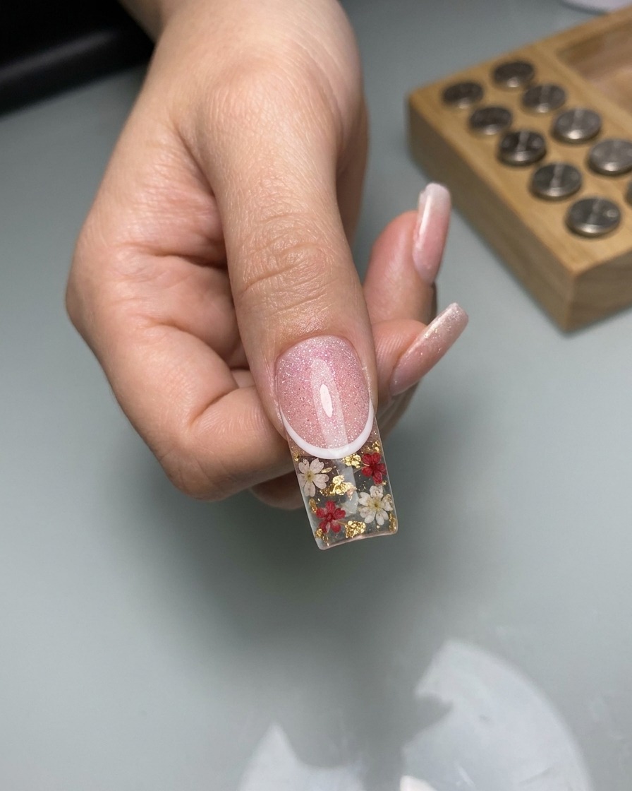 Gros plan montrant un pinceau liner traçant de fines lignes blanches en forme de dentelle sur la surface de longle cat-eye catalysé.