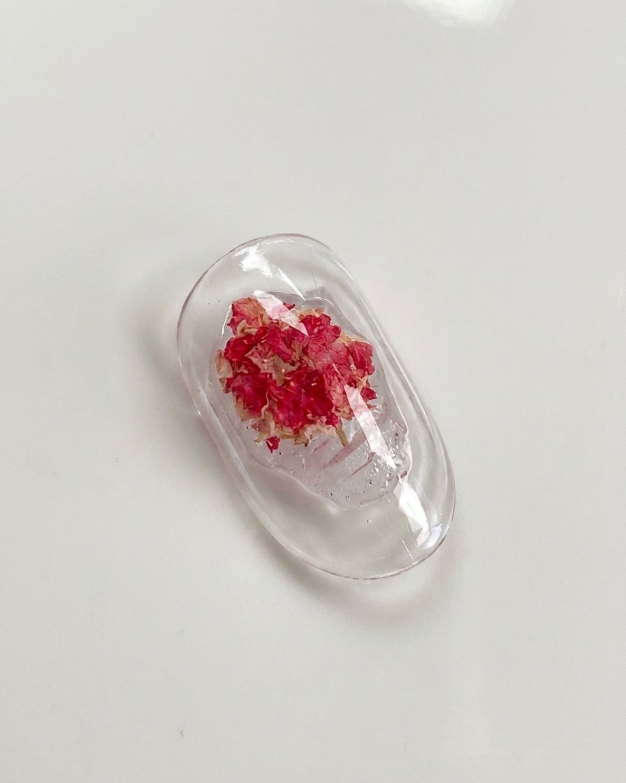 Un pinceau de précision pressant doucement les pétales dune rose séchée incrustée dans du gel.