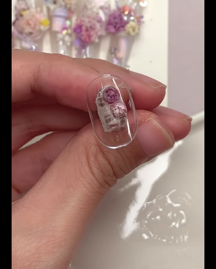 Un pinceau de précision pressant doucement les boules de fleurs sur un tip.